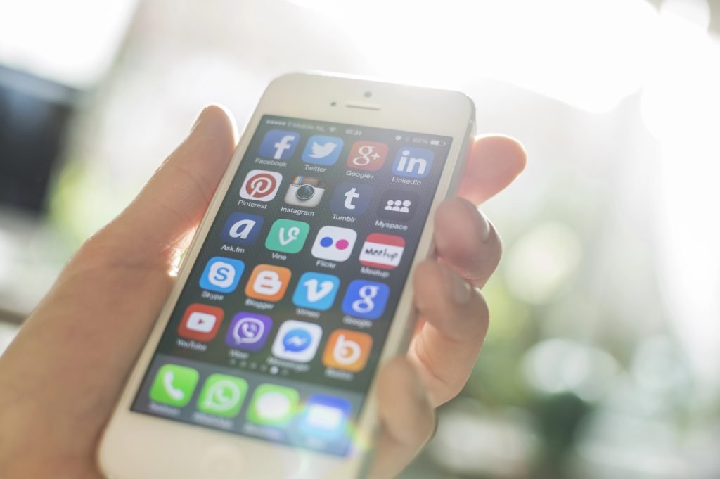 Smartphone displaying various social media app icons, emphasizing digital marketing and social media engagement for local businesses.