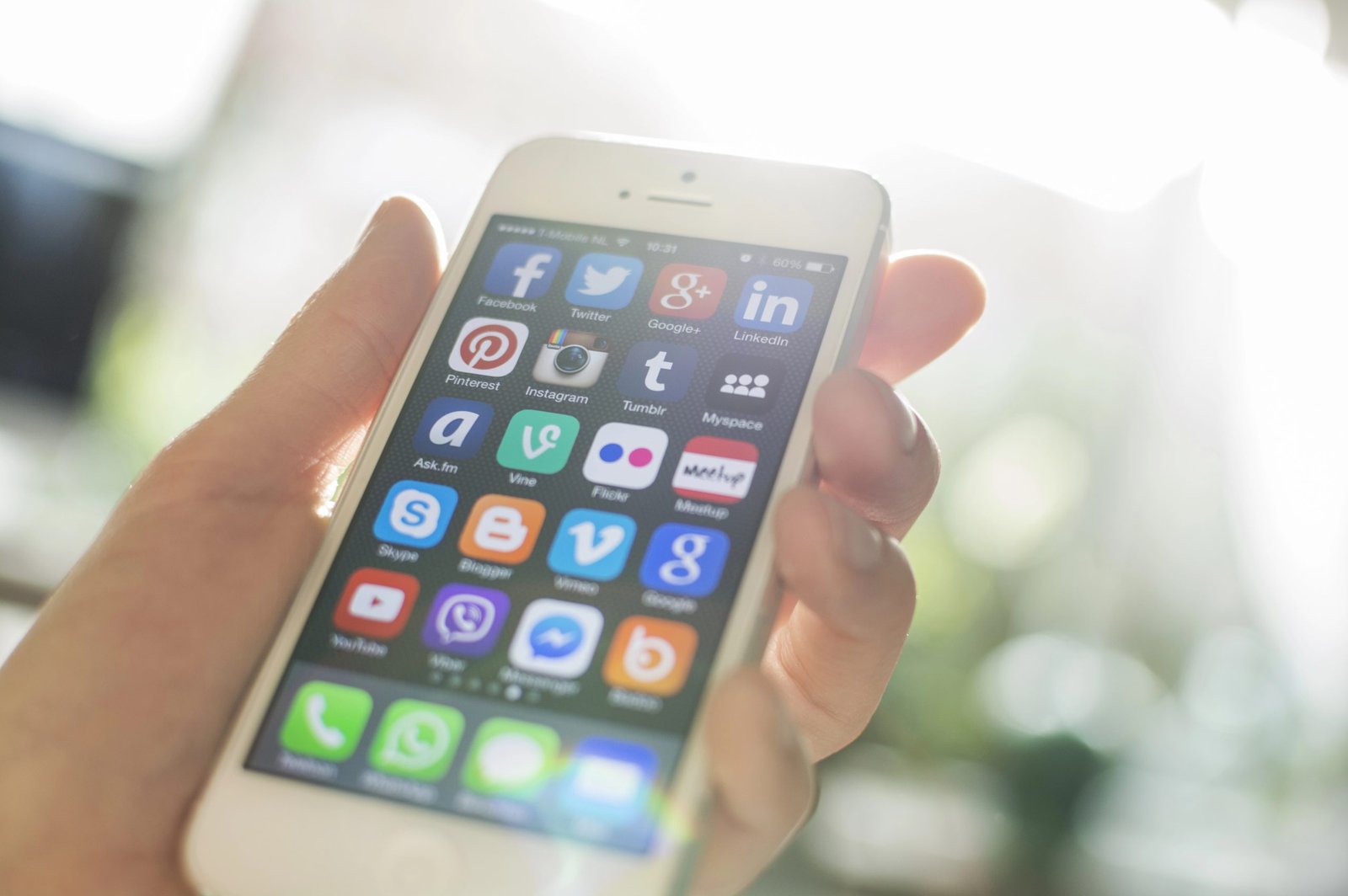 Hand holding a smartphone displaying various social media app icons, emphasizing digital marketing strategies for hospitality businesses.