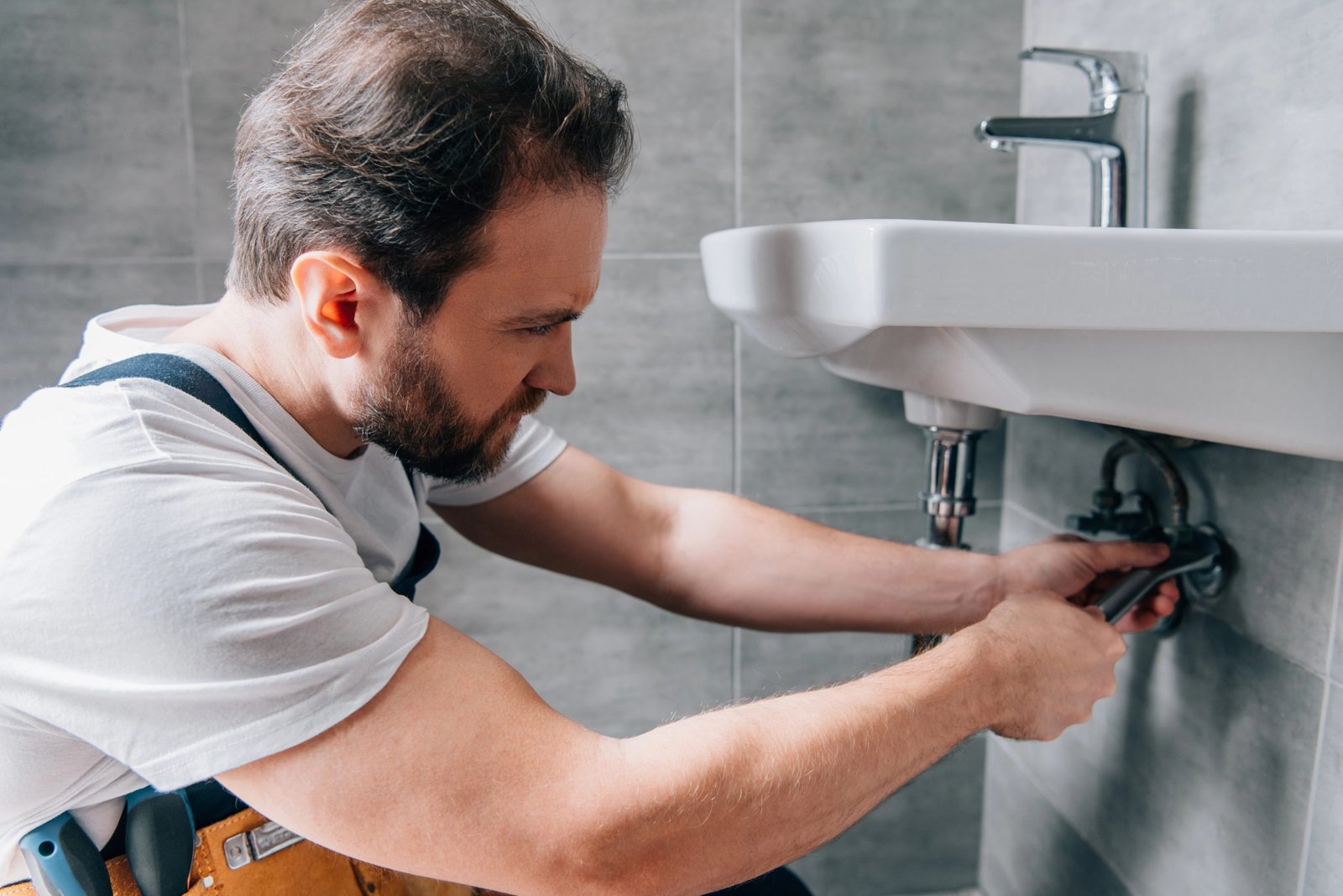 Plumber repairing sink plumbing, emphasizing home services and trust in urgent situations.
