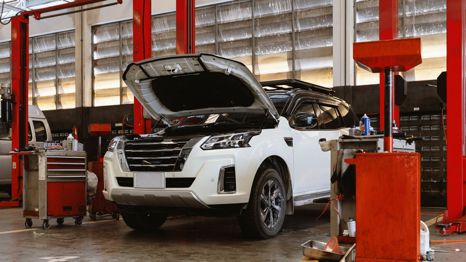 White SUV with hood open in an auto repair shop, surrounded by tools and equipment, emphasizing the focus on generating booked jobs for auto repair businesses.